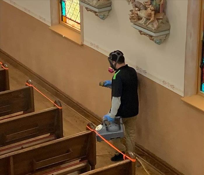 SERVPRO employee wearing proper PPE fogging a church for disinfection.